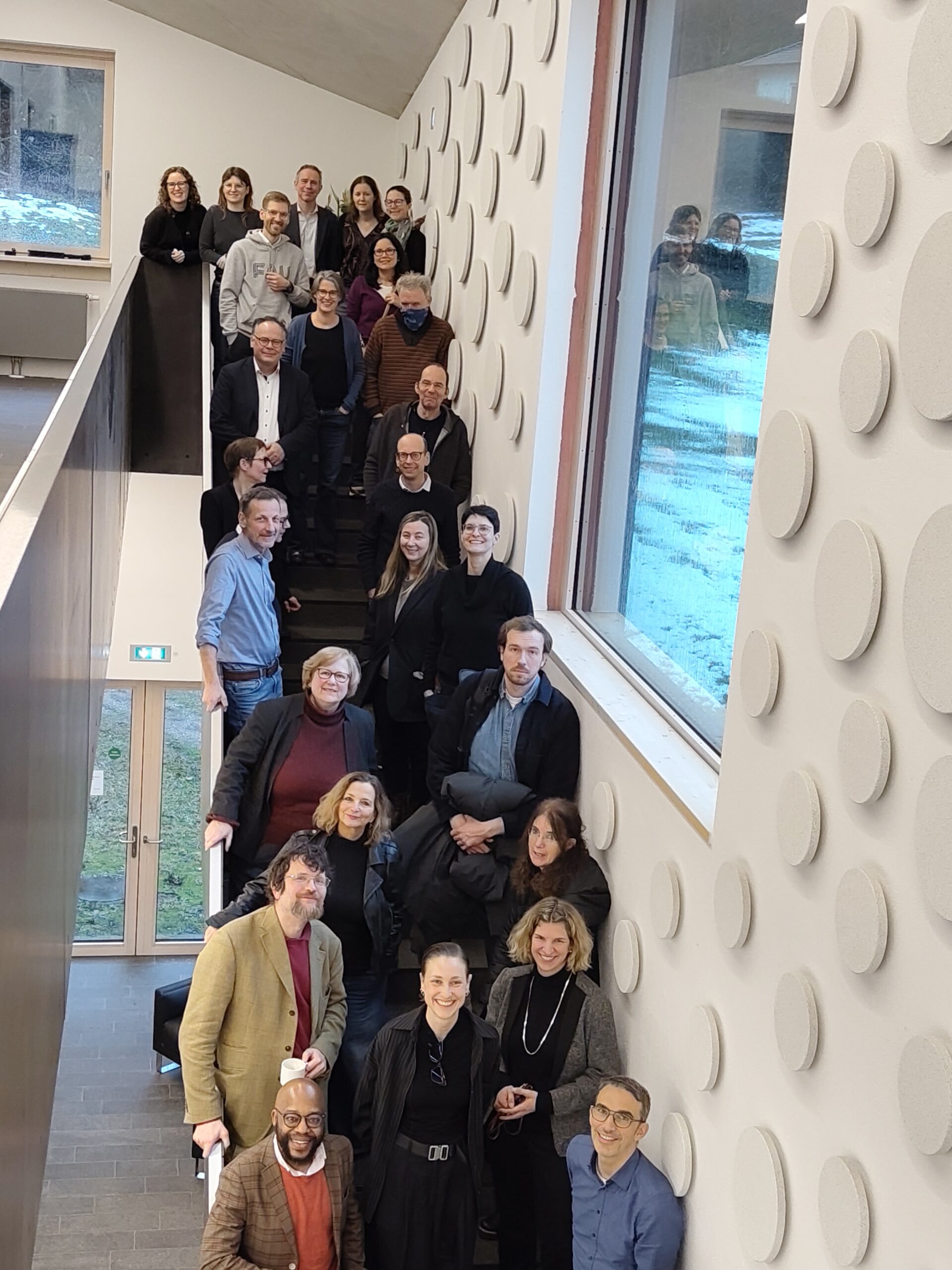 A mixed group of people stands on a staircase.